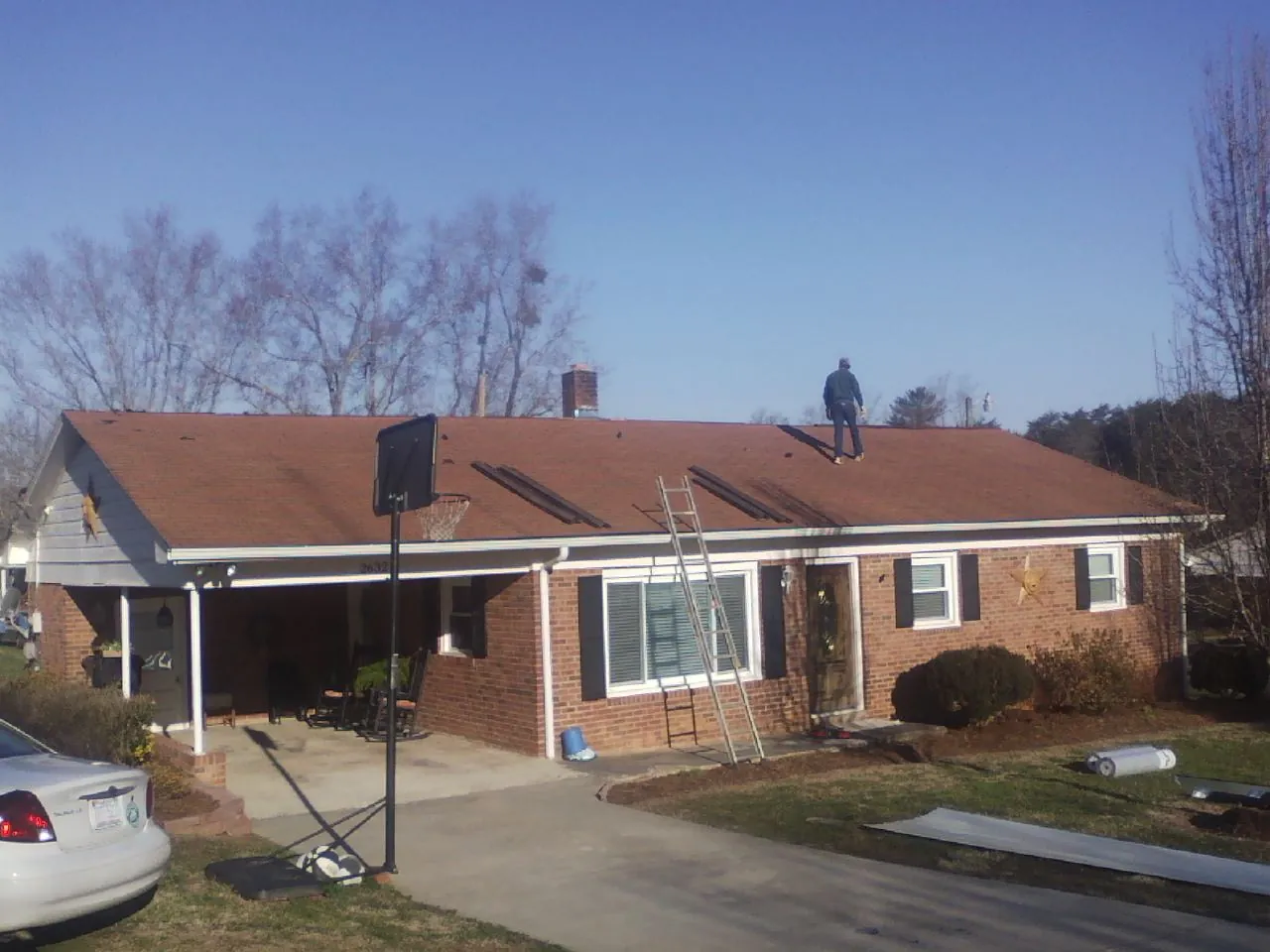 Roofer stripping a shingle roof on a brick ranch before metal panels in Kissimmee
