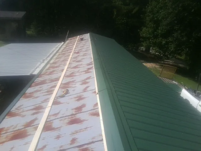 Old rusted panels beside newly installed green metal roofing — Wind Damage Roof Repair by Roofing Brothers in Kissimmee