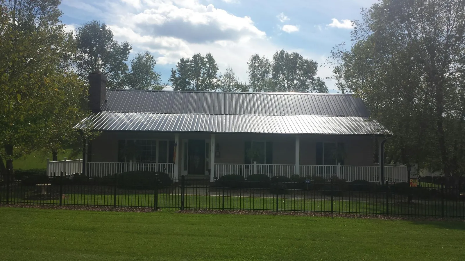 Gray metal roof on a brick ranch with a full width front porch — Gutter Guard Installation work by our crew in Kissimmee