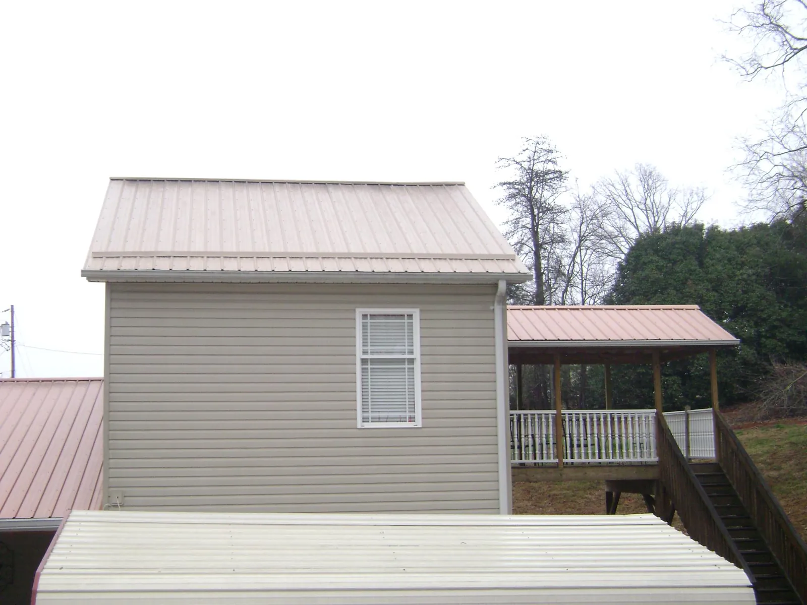 Tan metal roofs on a two story addition and attached porch, from a Roof Replacement job in Kissimmee