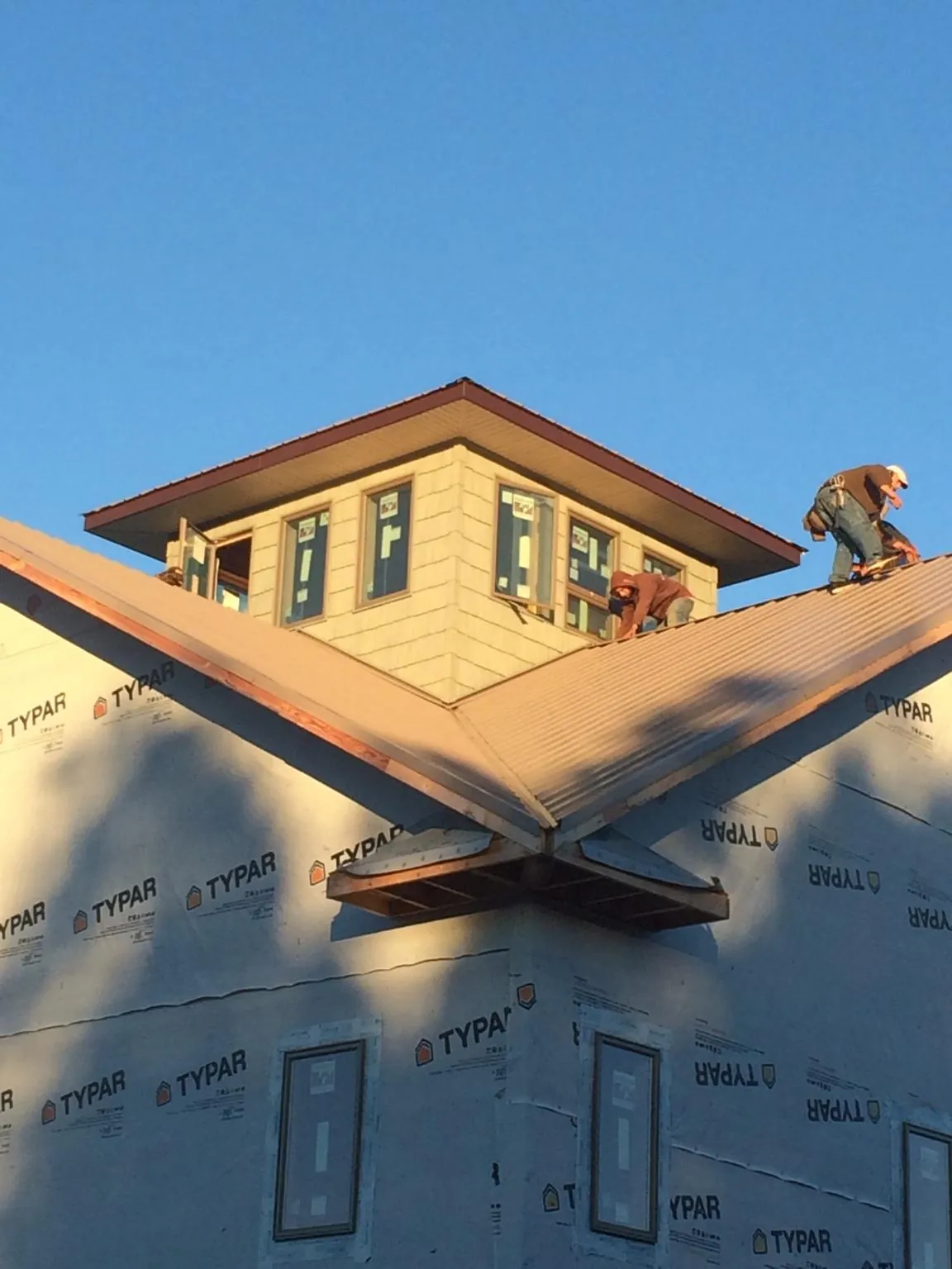 Roofers working around a rooftop cupola on a new metal roof at sunset — Roof Waterproofing in Kissimmee by Roofing Brothers